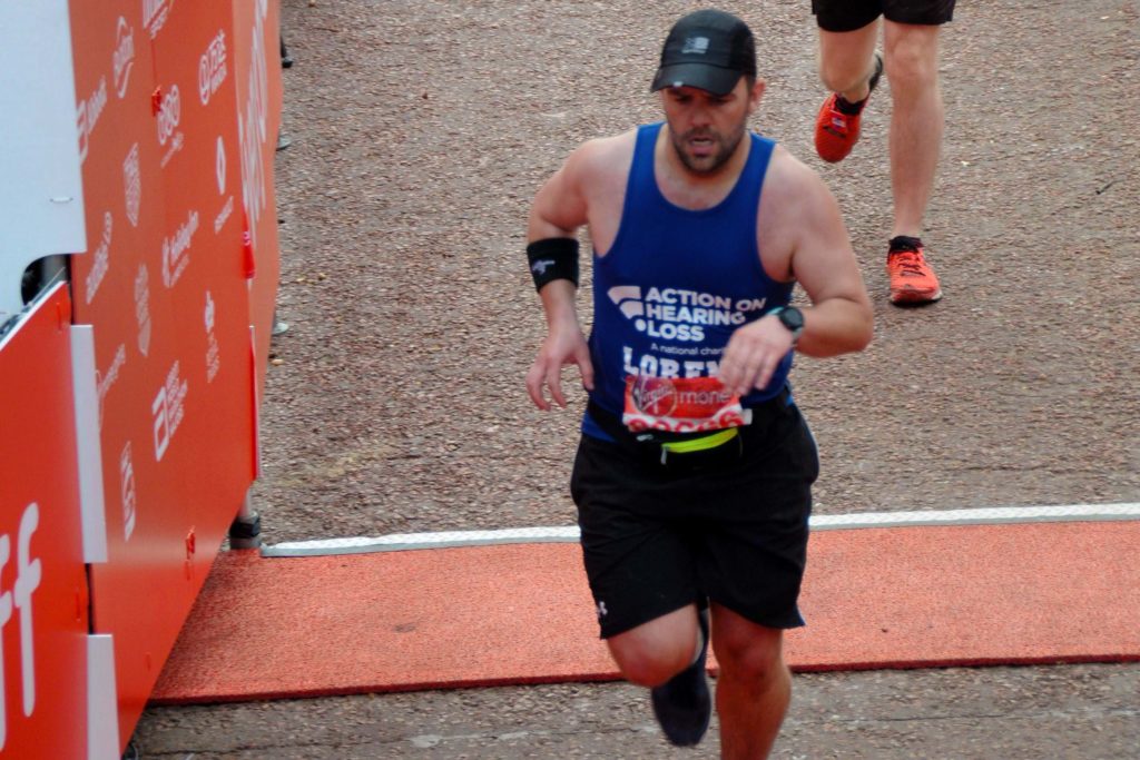 Lorenzo running a marathon wearing an Action on Hearing Loss vest top