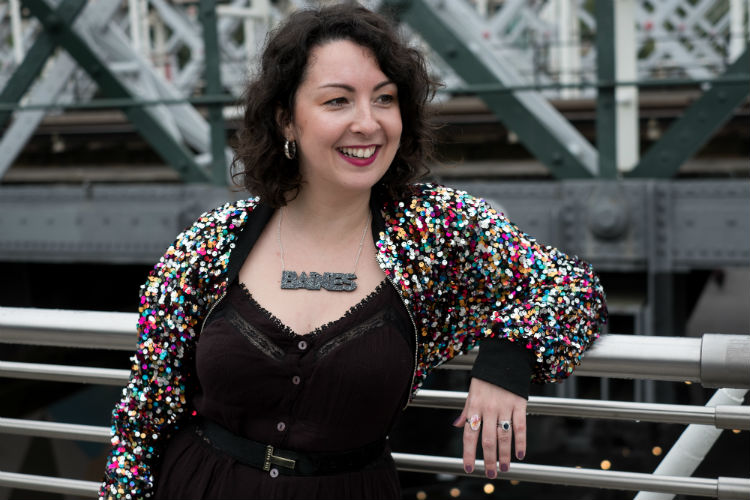 Samantha smiling wearing a black dress and colourful jacket
