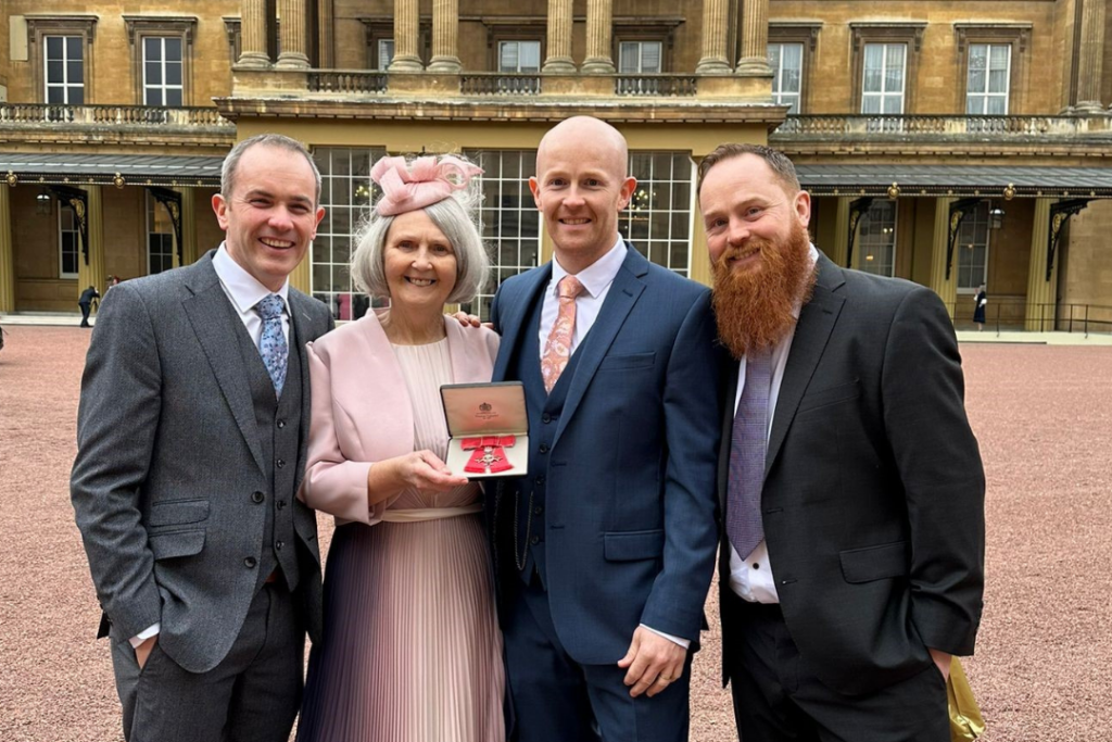 Hilary Lewis outside of Buckingham Palace with her sons, from left to right: Alan, Stephen and Paul.