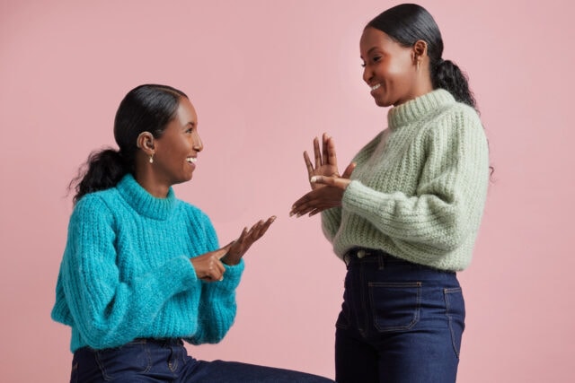 Two women face each other and communicate through British sign language (BSL).