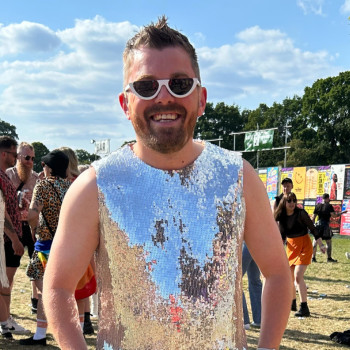 A photo of Chris wearing a sequin top and sunglasses outside, smiling with his hands on his hips.