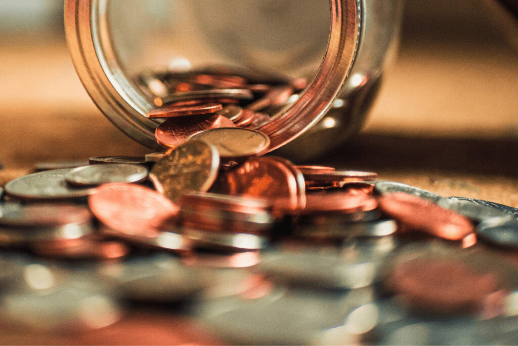 A jar of coins spilling over a table.