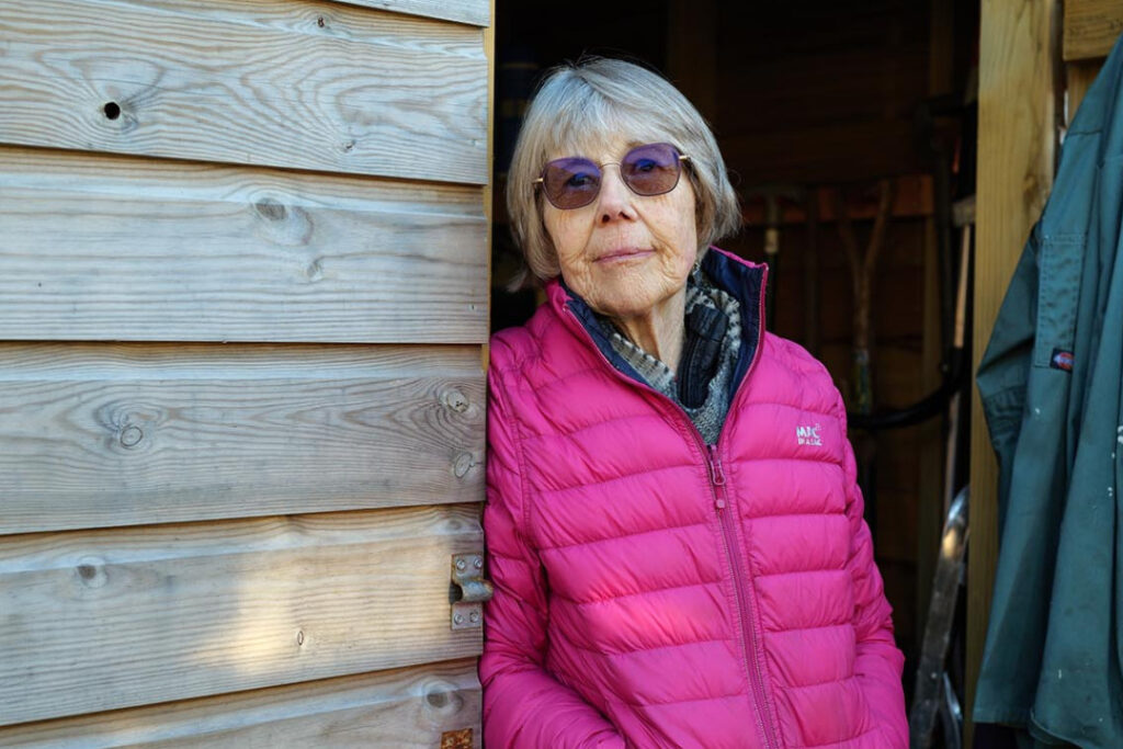 Helen Kendall outside, standing in the doorway of her garden shed. 