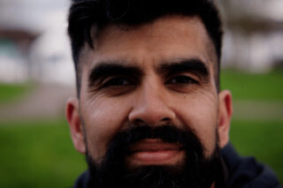 A close up image of a man with a beard smiling