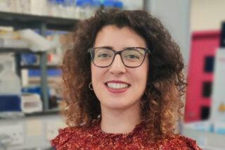 A photo of Dr Elisa Martelletti. She stands in the lab and smiles at the camera.