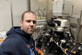 Dr Philippe Vincent sits beside scientific equipment.