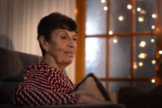 Woman sitting in her living room with Christmas lights in the background