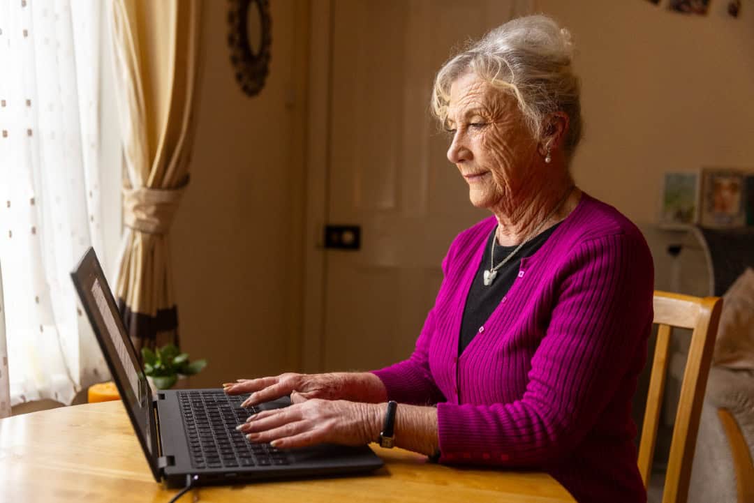 A woman in her home typing into her laptop