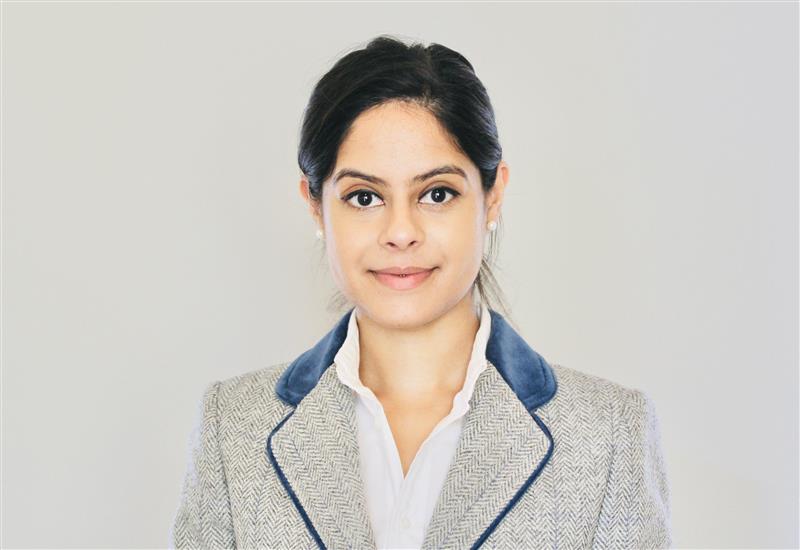 A photo of Dr Devina Maru. She faces the camera, wearing a smart jacket and smiling.
