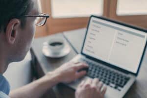 Person wearing a hearing aid using a laptop to fill out a website form, displaying concentration in a bright and clear workspace.