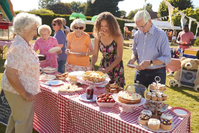 A group of people around a table of tea and cakes on a summers day.