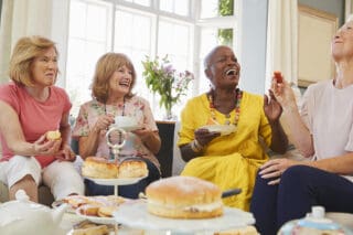 A group of people seated around a table enjoying tea and cake