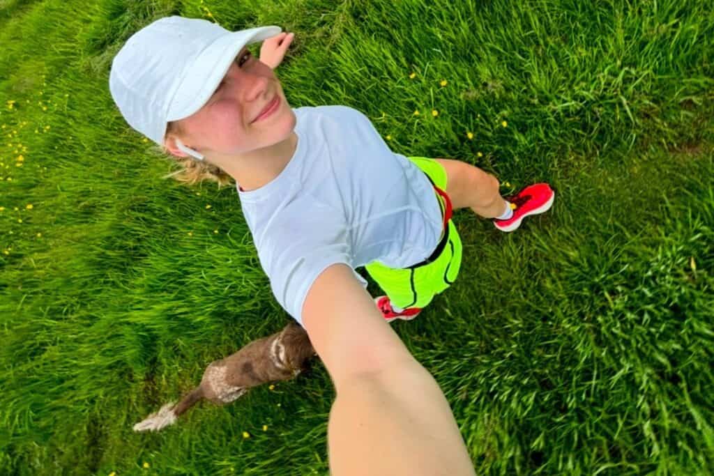 A selfie of Saskia running with her dog in a field, one of our London Marathon runners 2025