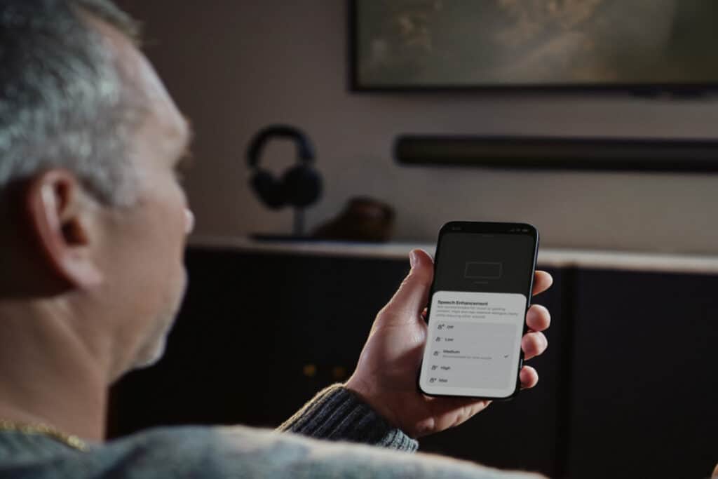 A man sat on his sofa and looking at his phone.