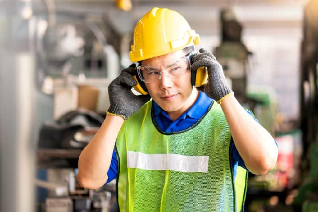 A person wearing protective, high vis clothing and ear protectors