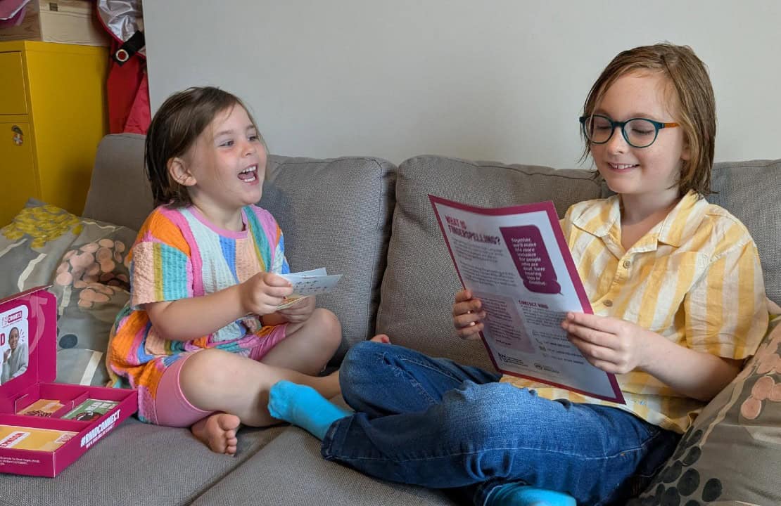 Two children laughing together on a sofa