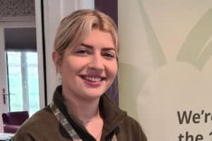 RNID volunteer, Rachel, wears a green RNID fleece and smiles.