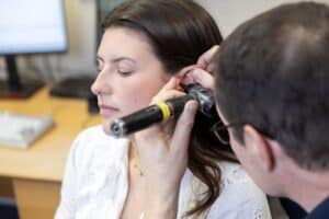 An audiologist inspecting a patient's ear