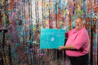 RNID storyteller, Dougie, poses with his painting created to represent his tinnitus.