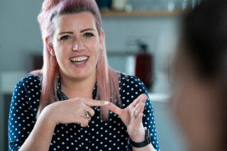 Woman smiling and using sign language in discussion with a colleague