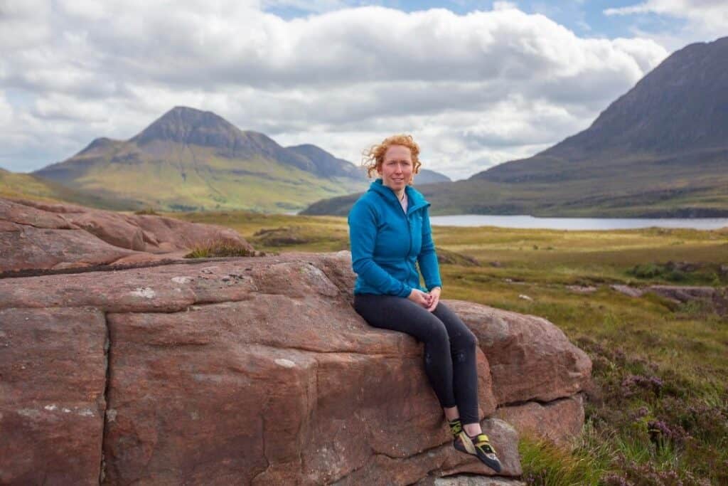 RNID storyteller, Morag, sits on a mountain edge in Scotland.