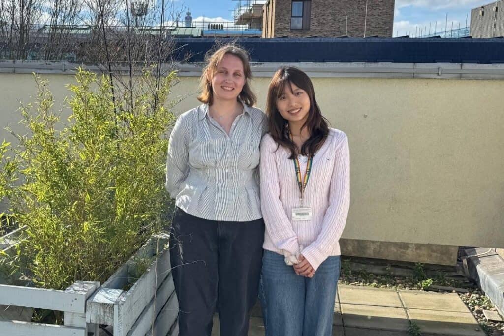 RNID-funded researchers, Eleanor and Xena, stand together by a river.