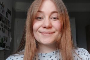 RNID staff member, Kirsty Reed, smiles. She has long brown hair.