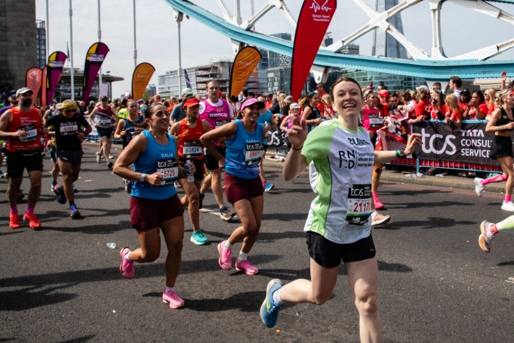 RNID supporter, Claire, runs the London Marathon. She waves and smiles as she runs past.