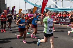 RNID supporter, Claire, runs the London Marathon. She waves and smiles as she runs past.