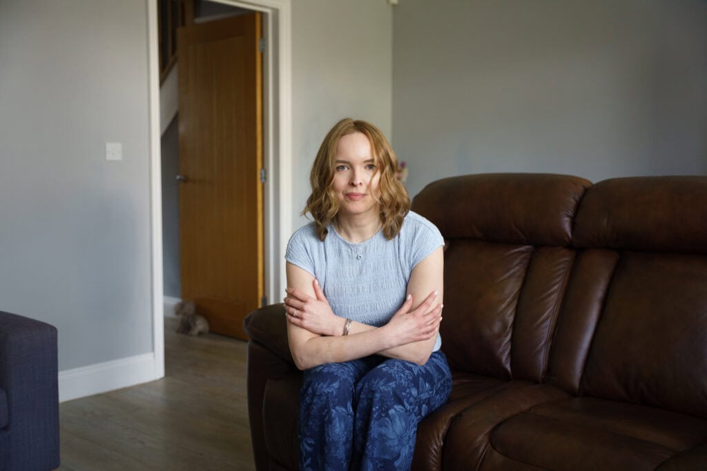 Storyteller Caroline sitting on her sofa at home