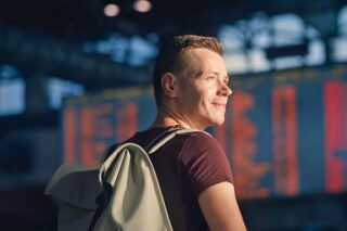 Person at a railway station with the train timetable in the background
