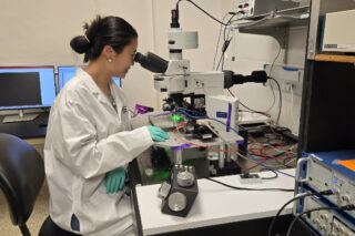 Biomedical researcher in a lab using a microscope