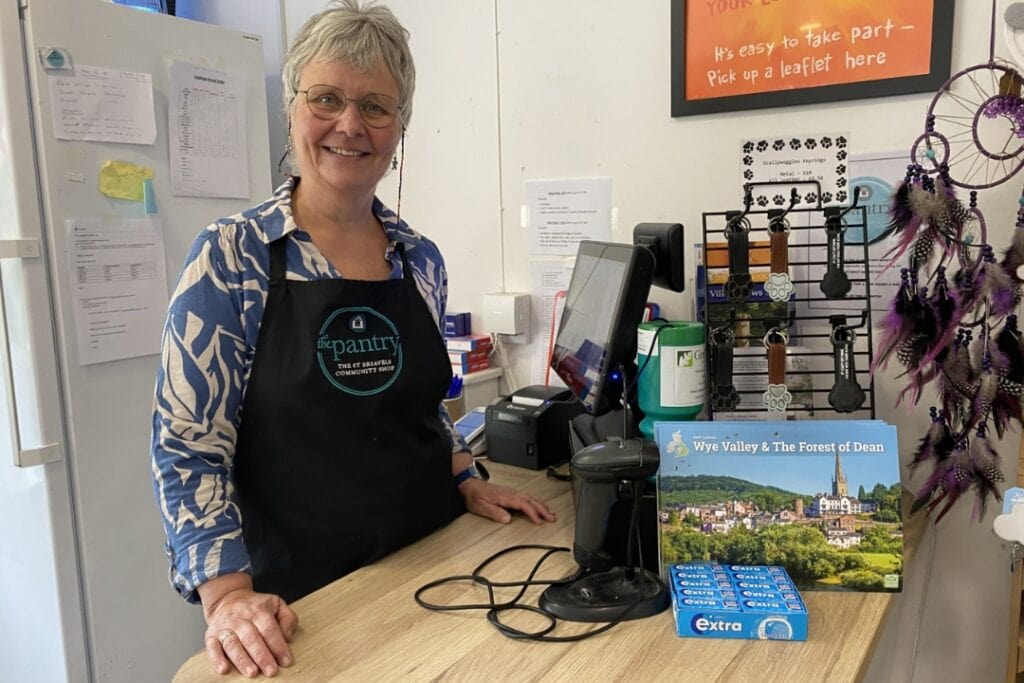 RNID storyteller, Mel, stands behind the counter in her community shop.