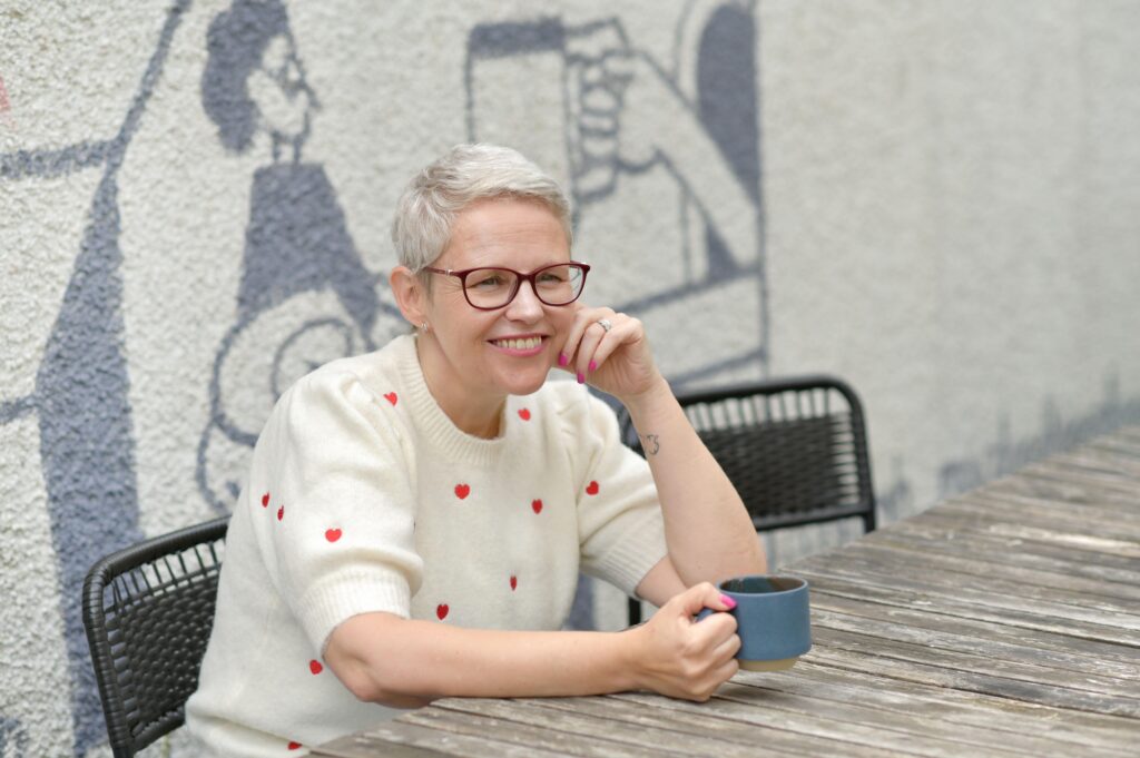 Storyteller, Sian, seated outdoors at a table, smiling