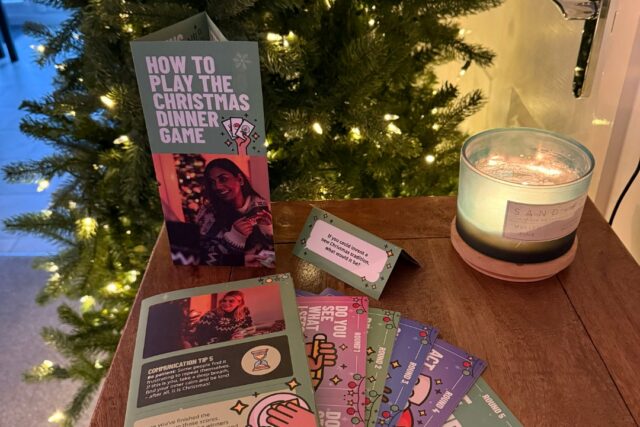 RNID's Christmas Dinner Game displayed by a Christmas tree and scented festive candle.