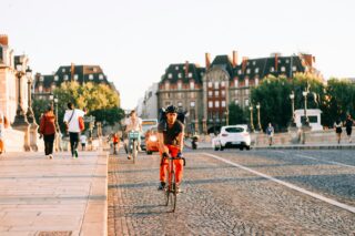 A man in red riding a bike over a bridge in Paris, France.