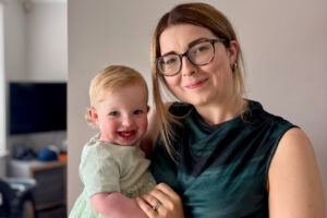 A woman wearing glasses holds her young daughter.